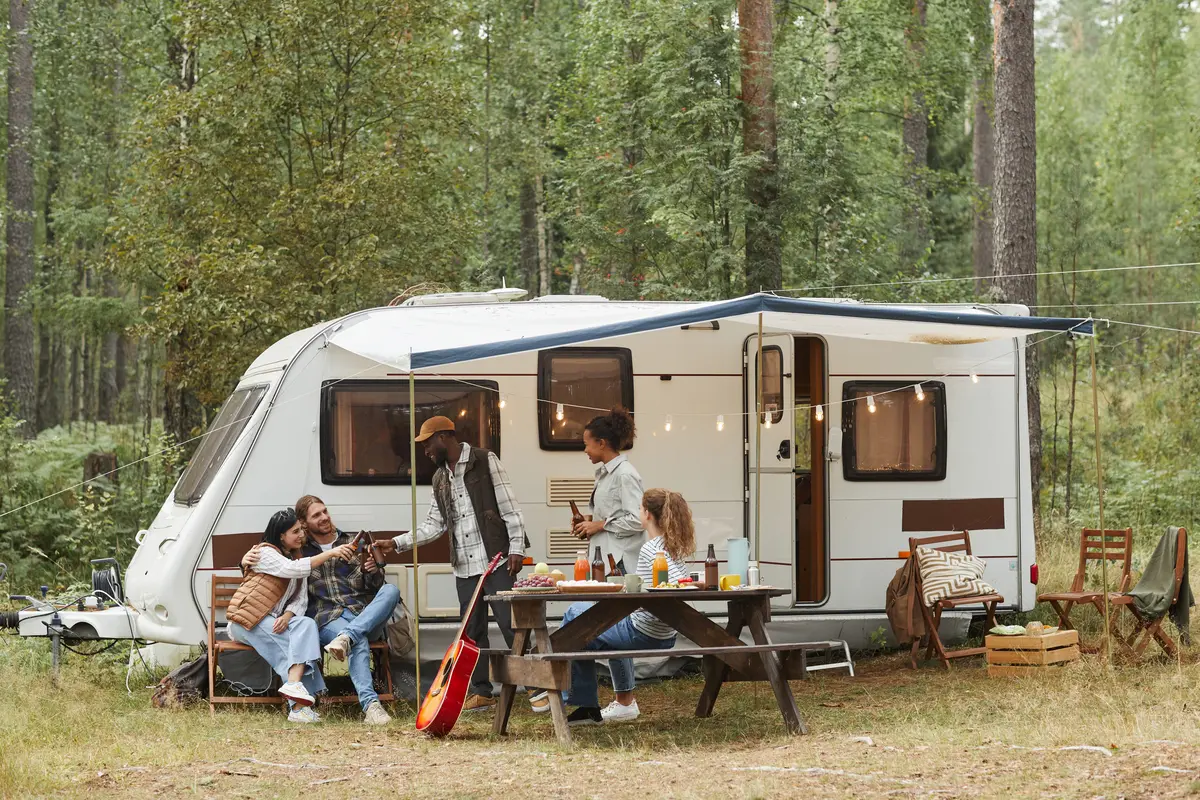 Friends enjoying a picnic by camper van.