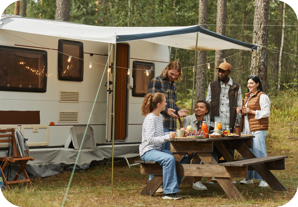 GettyImages-1344837112 Group enjoying picnic near camper in forest.