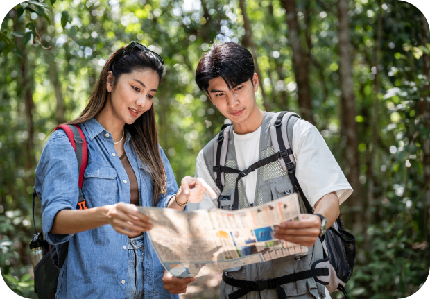 GettyImages-1959415111 Couple hiking and reading map in forest.